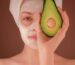 woman with white face mask holding green fruit